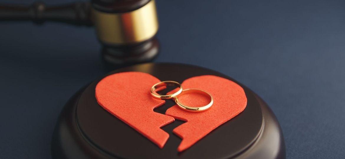 Wedding rings on the figure of a broken heart from a tree, hammer of a judge on a wooden background. Divorce