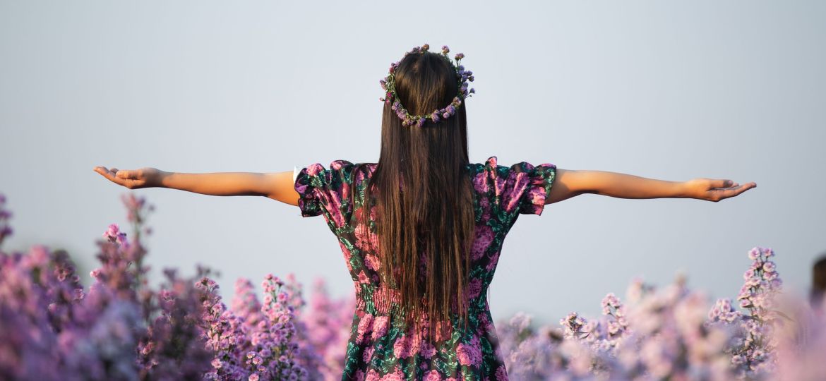 joyfull woman in purple dress among of purple margaret flower