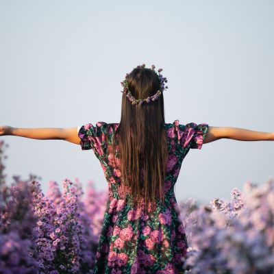 joyfull woman in purple dress among of purple margaret flower