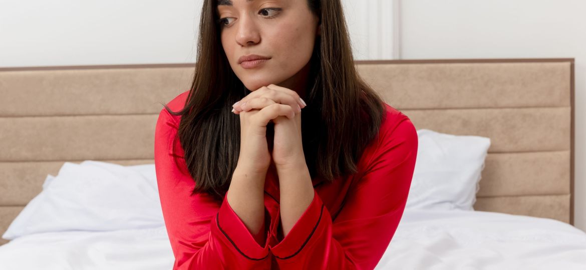 young-beautiful-woman-red-pajamas-sitting-bed-looking-aside-with-sad-expression-face-bedroom-interior-light-background